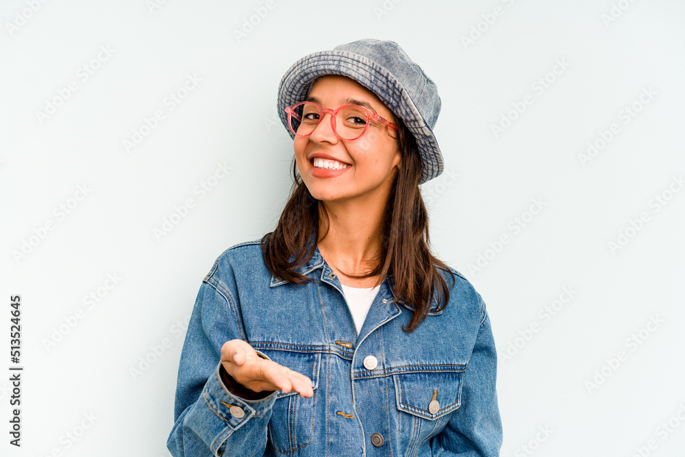 Young hispanic woman isolated on blue background excited holding a copy space on palm. Young hispanic woman isolated on blue background excited holding a copy space on palm.