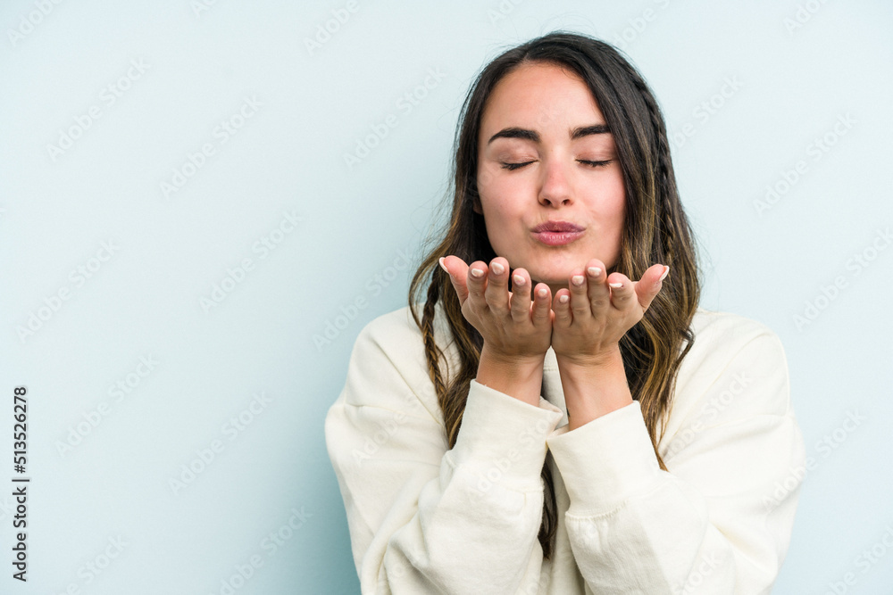 Young caucasian woman isolated on blue background folding lips and holding palms to send air kiss. Young caucasian woman isolated on blue background folding lips and holding palms to send air kiss.