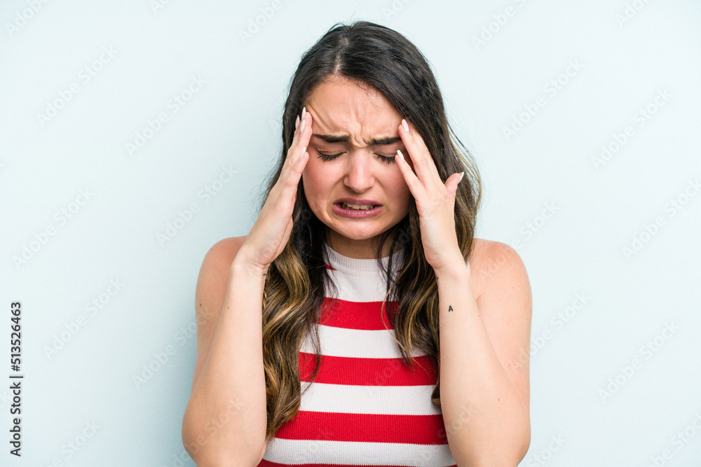 Young caucasian woman isolated on blue background having a head ache, touching front of the face. Young caucasian woman isolated on blue background having a head ache, touching front of the face.