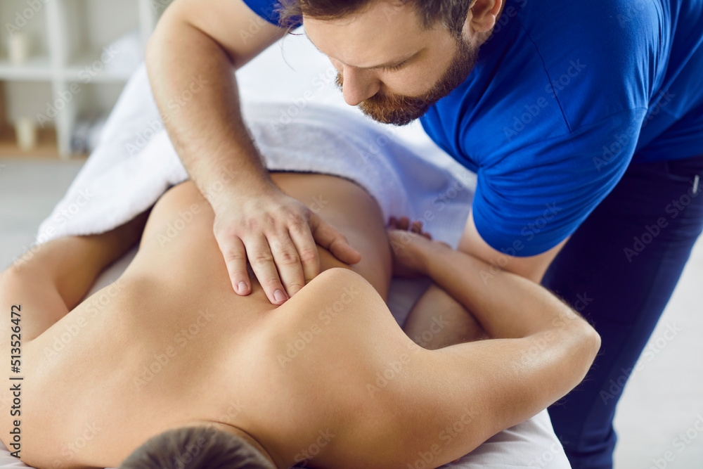 Obraz premium Closeup of man physiotherapist make back massage to client in spa or studio. Male masseur use manual technique relieve strain muscles and backache for customer. Physiotherapy and healthcare.