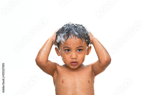 Cute asian boy taking a shower with shampoo in his hair. selective focus - isolated on white.