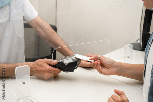 Adult woman paying for visit in dentist office in the medical clinic with card.