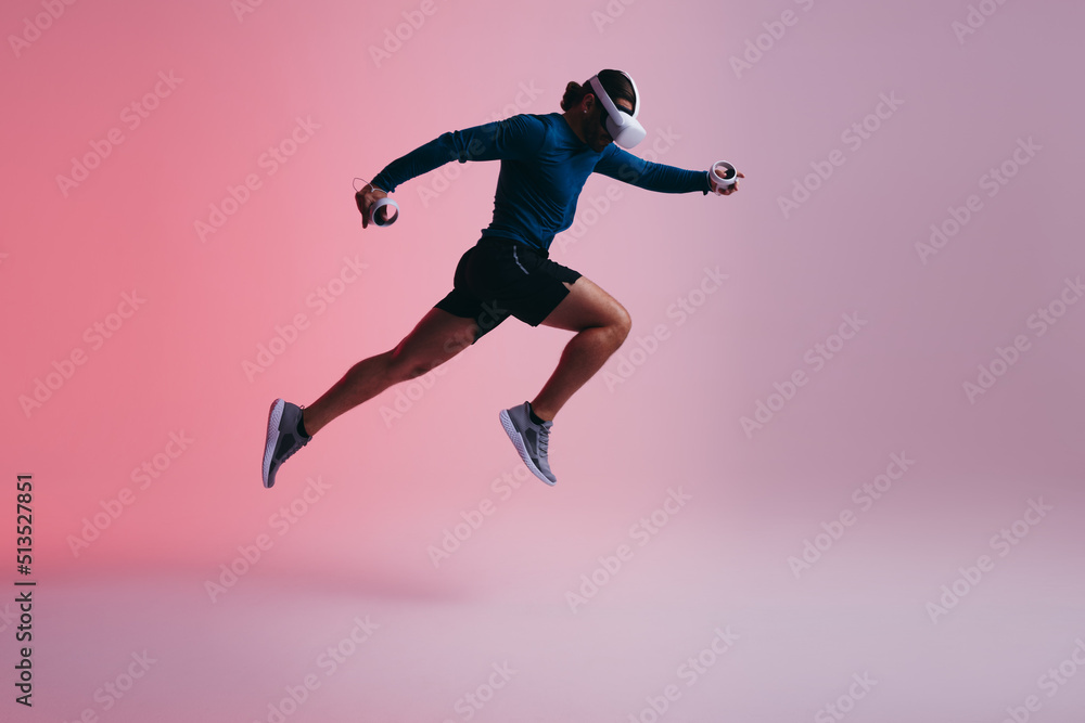 Athletic young man running mid air with virtual reality goggles Athletic young man running mid air with virtual reality goggles
