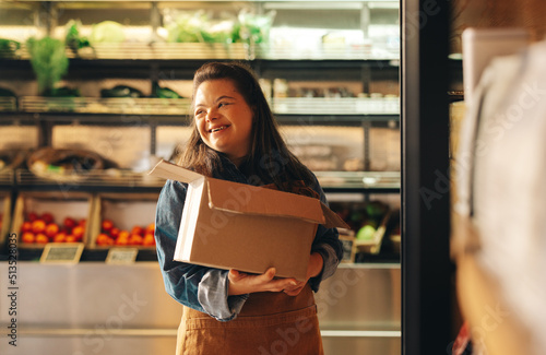 Print op canvas Smiling woman with Down syndrome working in a grocery store