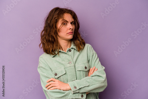 Young caucasian woman isolated on purple background suspicious, uncertain, examining you. © Asier