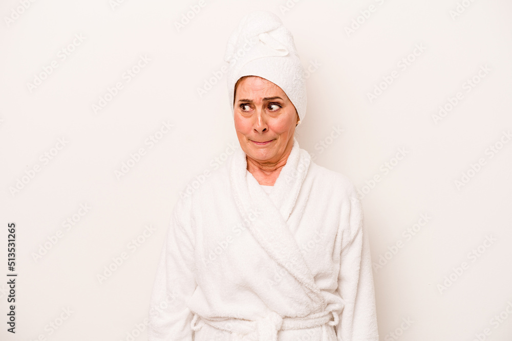 Middle age caucasian woman wearing a bathrobe isolated on white background confused, feels doubtful and unsure.
