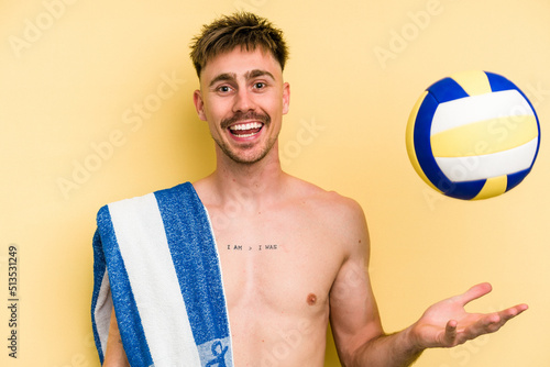 Young caucasian man playing volleyball isolated on yellow background