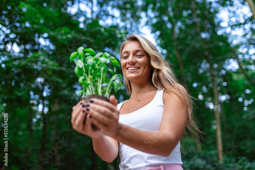 Young beautiful woman holding a plant growing out of soil