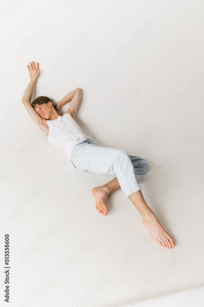 Aerial view of young handsome man, teen, student wearing casual clothes isolated over white background. Concept of fashion, youth, emotions, facial expression, ad