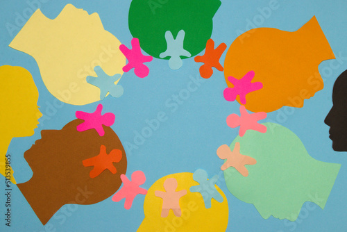 colorful paper head lined up in a circle around the circle that first and head lined up small colorful paper people in the middle copy space, pastel blue background looking at a man and a woman