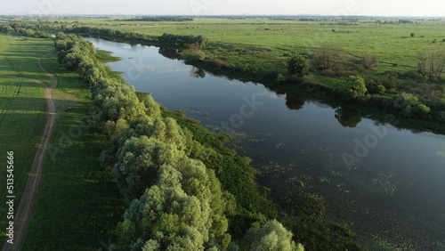 Aerial view of the road and trees along the river bank on a summer evening