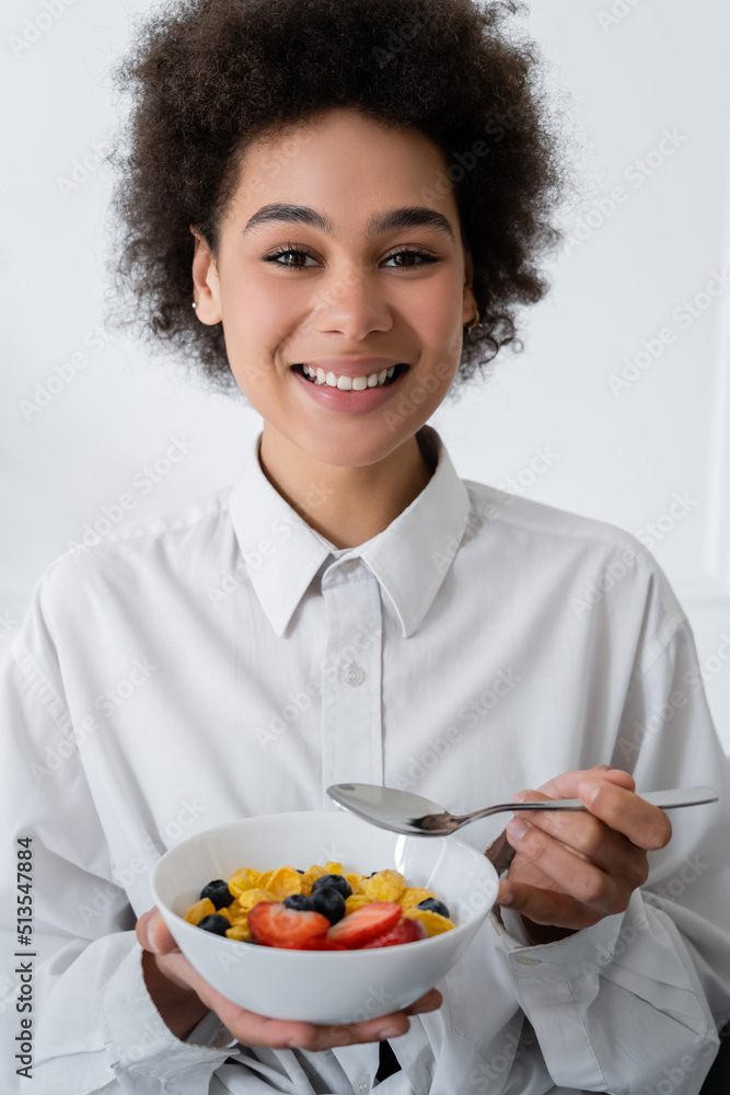 cheerful african american woman holding bowl with corn flakes and berries. cheerful african american woman holding bowl with corn flakes and berries.