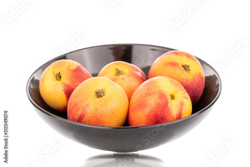 Several juicy organic nectarines with a ceramic plate, close-up, isolated on a white background.