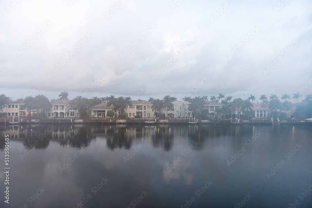 Cloudy foggy mist morning in Hollywood Beach in Miami, Florida Stranahan river and view of waterfront villas houses with palm trees and calm water reflection