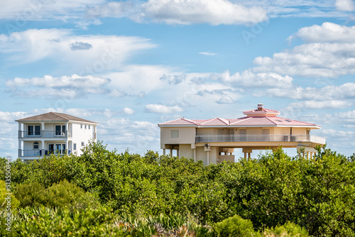 Colorful stilted vacation oceanfront waterfront homes houses on stilts of Atlantic ocean beach by mangrove forest in summer of Palm Coast on Crescent Beach, Florida photo