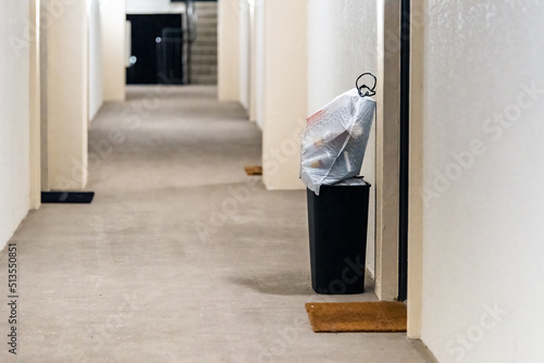 Concierge valet door to door trash collection services for apartment with garbage in bin and plastic bags for pick up in residential building hallway corridor hall photo
