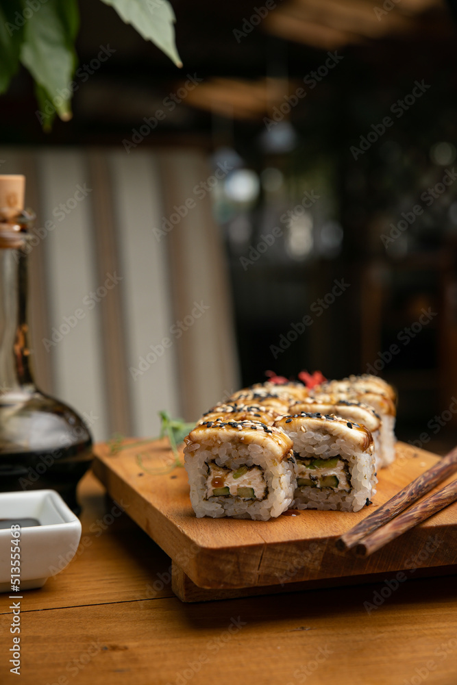 Japanese cuisine. Rolls with sauce on a wooden plate
