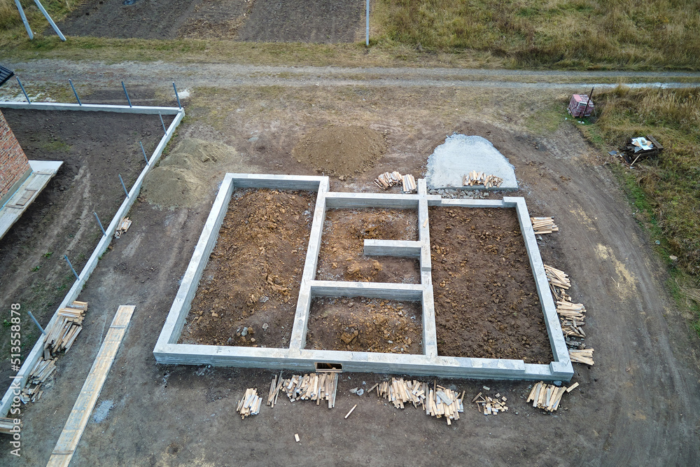 Fototapeta premium Top down aerial view of building works of new house concrete foundation on construction site