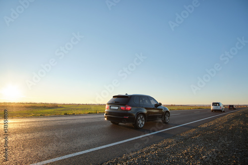 SUV car driving fast on intercity road at sunset. Highway traffic in evening