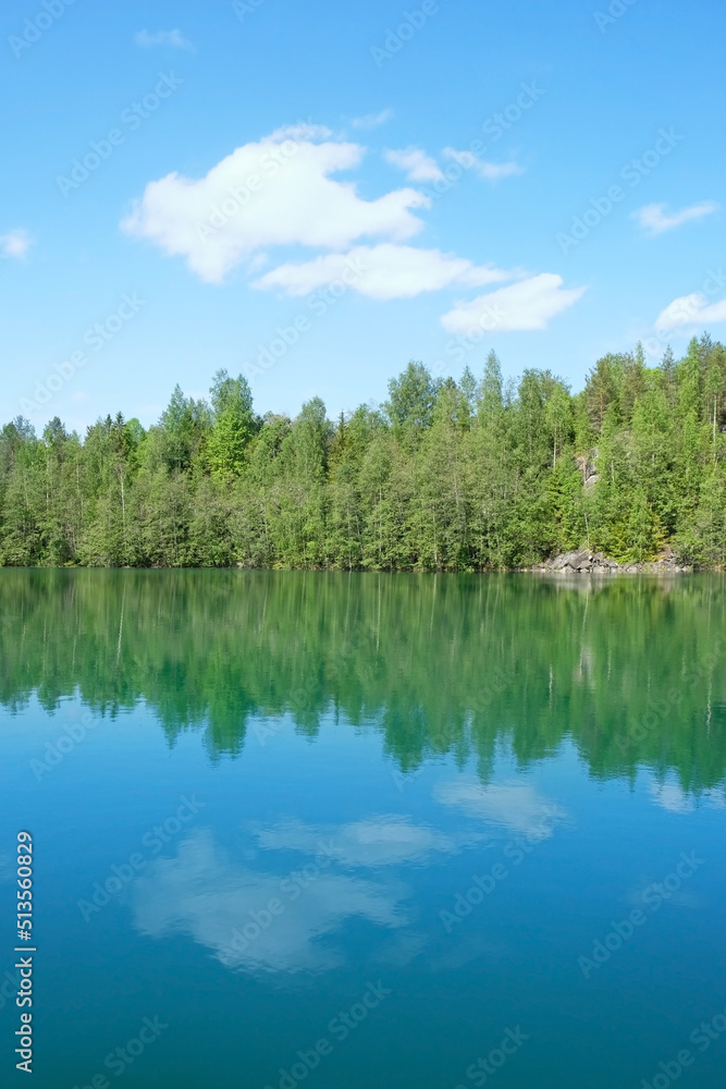 Obraz premium Beautiful blue lake, green forest and blue sky. Lakeshore Summer peaceful landscape in sunny day. scenic minimal view. Northern nature of Karelia