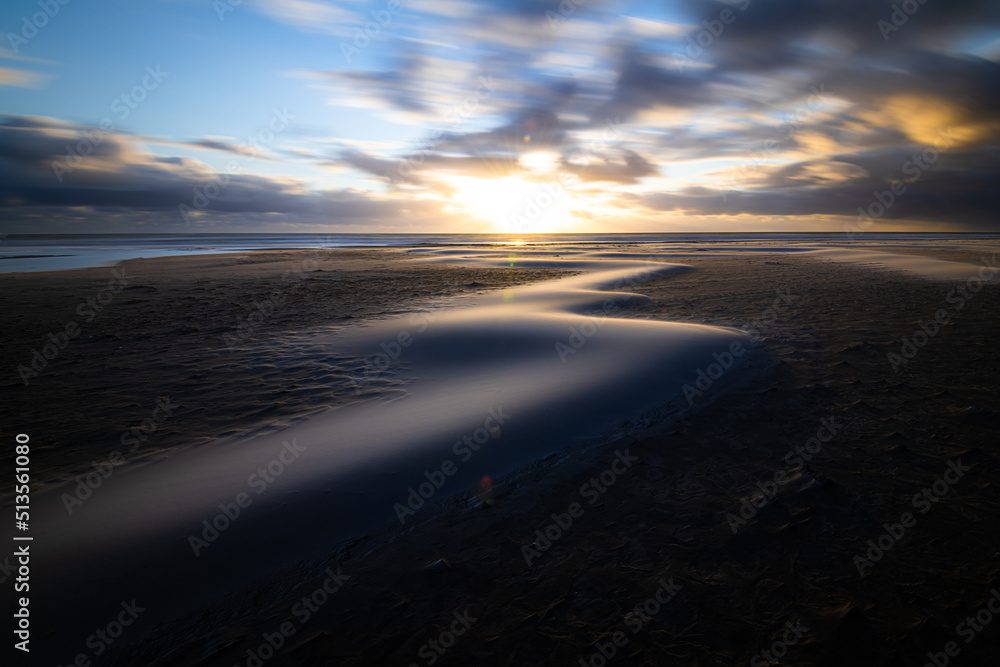 Scenic moving sand dunes at the beach of Amrum island Germany on a windy evening during sunset with drifting clouds Scenic moving sand dunes at the beach of Amrum island Germany on a windy evening during sunset with drifting clouds