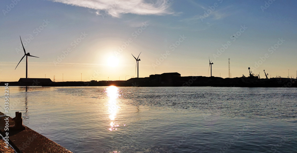 Danish wind turbines producing electricity by the west coast in sunset Danish wind turbines producing electricity by the west coast in sunset