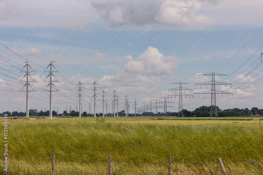 Fototapeta premium Expansion of the high-voltage grid with many high-voltage pylons to meet the growing demand for electricity, photo taken in the province of Groningen, the Netherlands