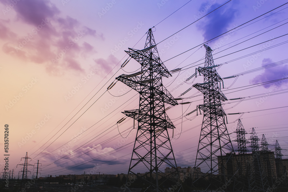 Silhouette of high-voltage electrical towers on a sunset background.