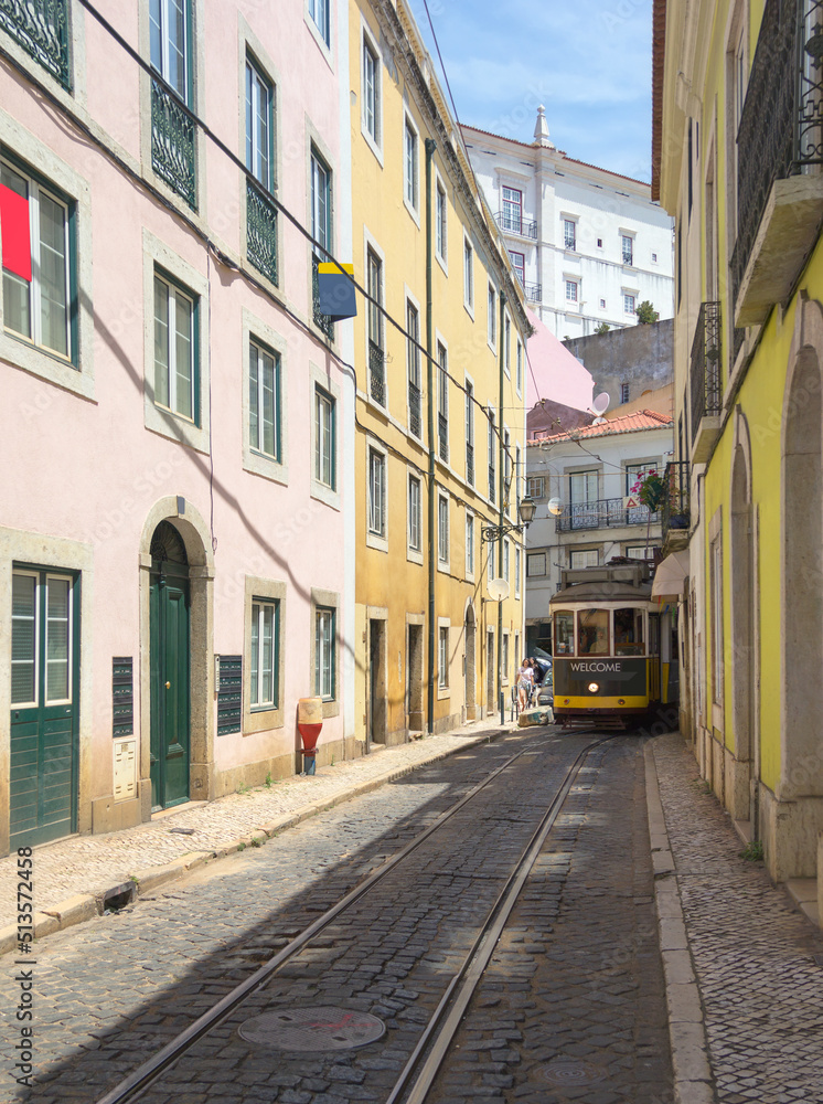 The tram runs along narrow street of Alfama district. Lisbon, Portugal.