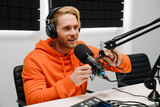 Young male radio host using microphone while broadcasting in studio