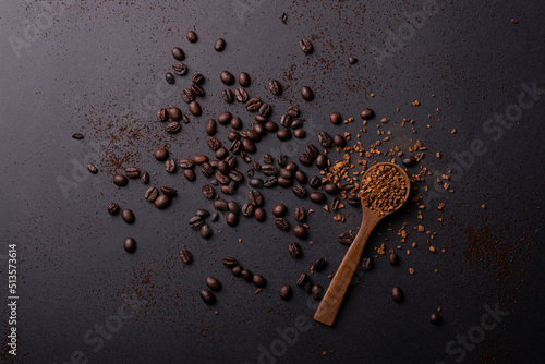 Scattered coffee beans accompanied by a spoon full of instant coffee on the right. Top view plane.