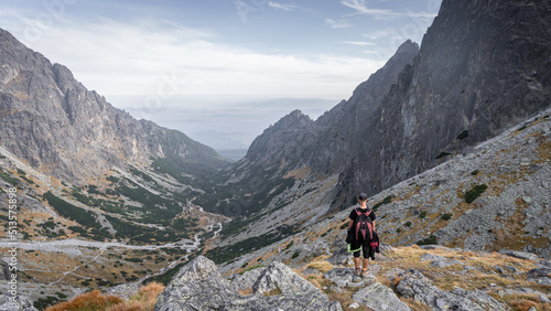 Hiker enjoying the view on alpine valley with big mountains and autumn colours, Slovakia, Europe