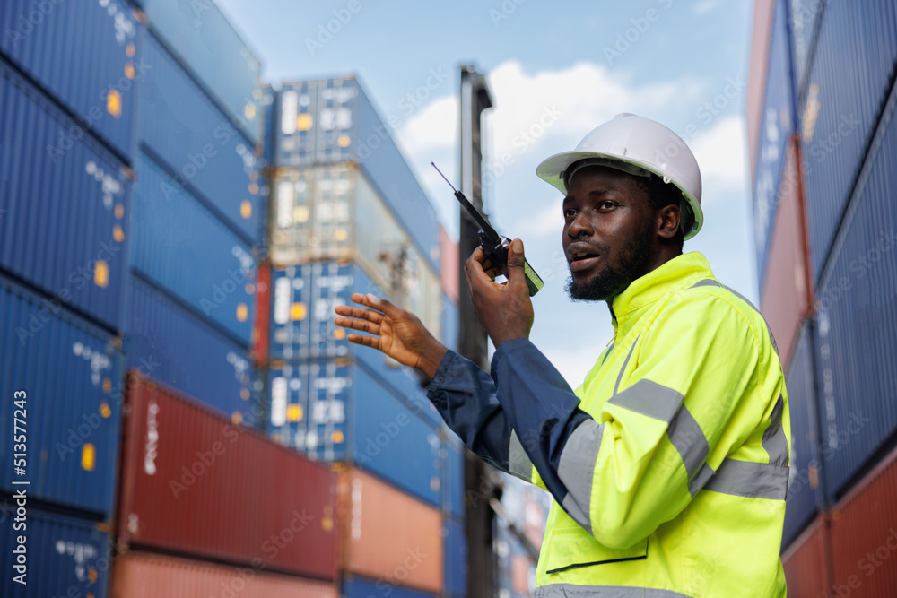 the african woker using walky talky comunicate with lifting container team with blue sky. Logistics transportation industry forklift handling container box loading stacker. the african woker using walky talky comunicate with lifting container team with blue sky. Logistics transportation industry forklift handling container box loading stacker.
