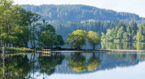 Loch view, Highlands of Scotland, UK. The trees overlooking the loch are reflected in the water.  photo