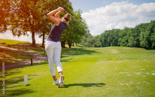 Sporty woman golfer player doing golf swing tee off on the green evening time, she presumably does exercise. Healthy Lifestyle Concept. Healthy Sport.