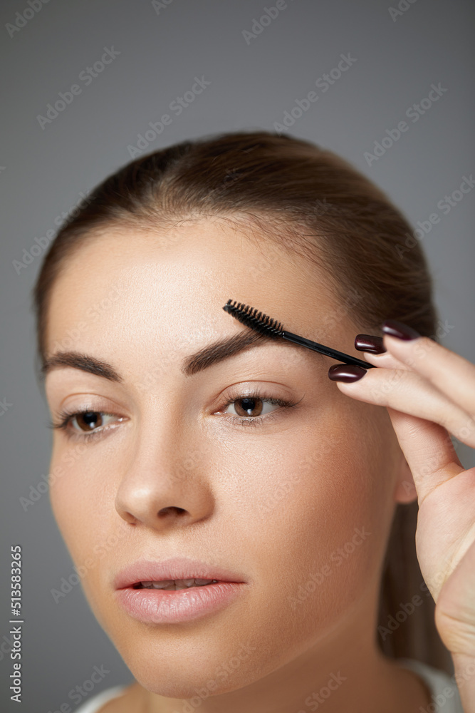Closeup Of Woman Beautiful Perfect Shaped Brow, Long Eyelashes With Professional Makeup And Brow Brush. Young Female Model Shaping Brown Eyebrows.