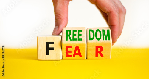 Freedom from fear symbol. Businessman turns wooden cubes and changes the concept word Fear to Freedom. Beautiful white background, copy space. Business, motivational and freedom from fear concept.