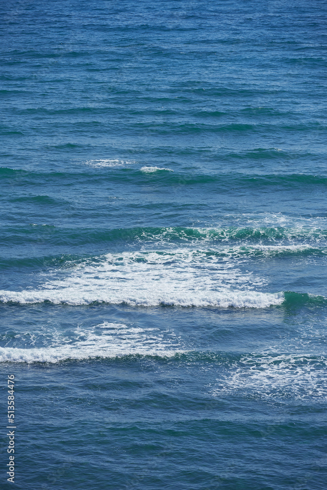 Fototapeta premium Calm waves in the empty ocean on a sunny day. Beautiful sea water with light ripple effects on the surface. Abstract aqua textures in the deep wide sea. White foam patterns in the Atlantic or pacific
