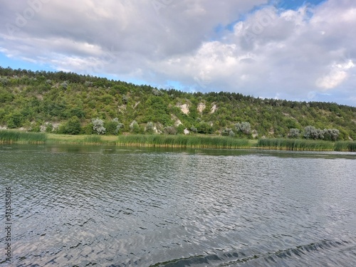 View from the middle of the river to the hilly banks overgrown with forest