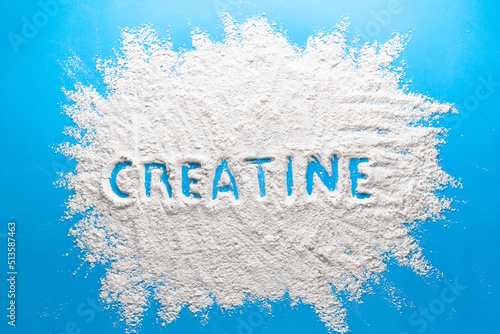 Scattered powder with the word creatine written on it on a blue background. photo