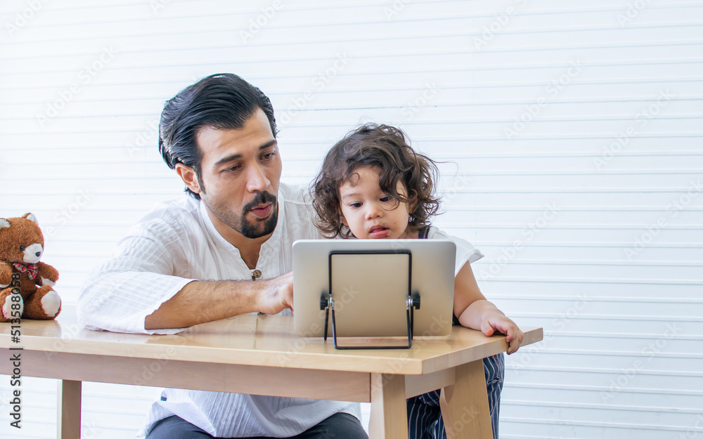 Obraz premium Caucasian handsome father and adorable little daughter playing together and online chatting in tablet while staying in living room at home. Family, Kid, Education and Technology Concept.