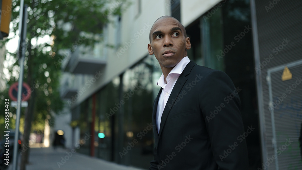 Adult african american businessman wearing suit walking along street