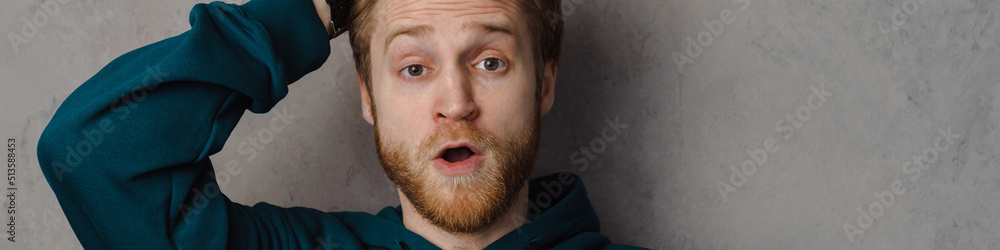 Fototapeta premium Bearded ginger man holding his head while expressing surprise