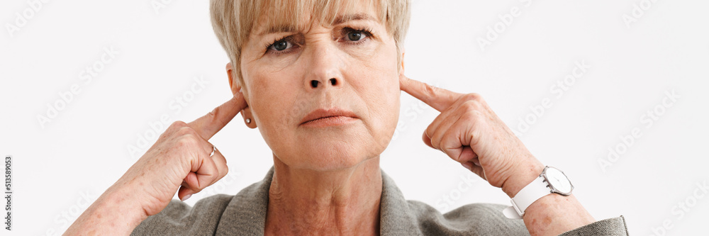 Fototapeta premium European mature woman frowning and plugging her ears