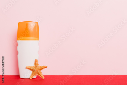 Beach accessories. Moisturiser sunscreen suntan lotion bottle for UVB skincare protection in summer with seashells on colored background. Mock up with copy space