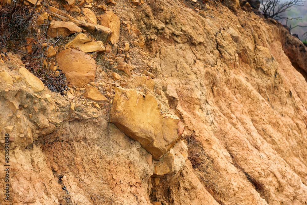 Closeup of crumbling dirt mountainside. Brown textured stone or clay cliff wall. Rough orange mountain environment. Copyspace nature scene for background. Outdoor surface for bouldering and climbing