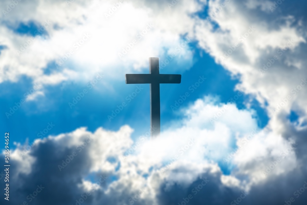 Silhouette of Christian cross over clouds against sky in the background. Easter religion faith concept