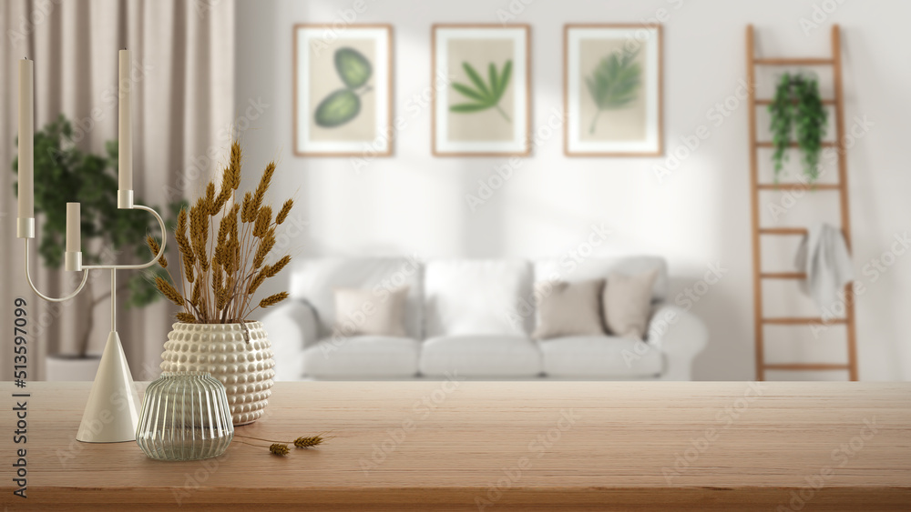 Naklejka premium Wooden table, desk or shelf close up with ceramic and glass vases with dry plants, straws over blurred view of scandinavian living room with sofa, modern interior design concept