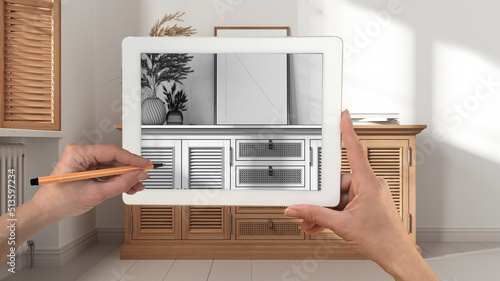 Hands holding and drawing on tablet showing modern wooden rattan chest of drawers details CAD sketch. Real finished interior in the background, architecture design presentation