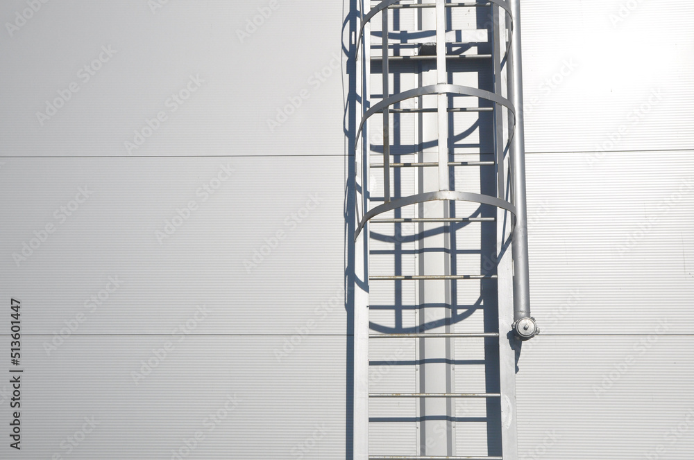 a fire escape leading to the roof of a building made of metal structures and a pipe for connecting a fire hose.